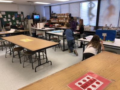photo of classroom of tables and groups working at some of them