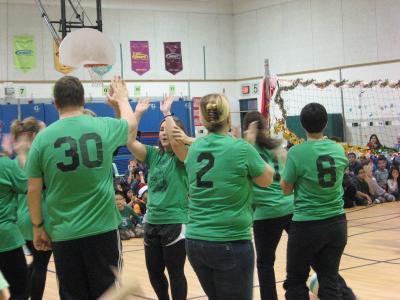 photo of teachers playing volleyball all wearing green tshirts