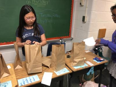 photo of students standing by desks with empty paper bags