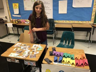 photo of students standing by desks with handmade items 
