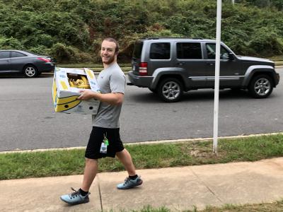photo of pe teacher carrying a box of bananas