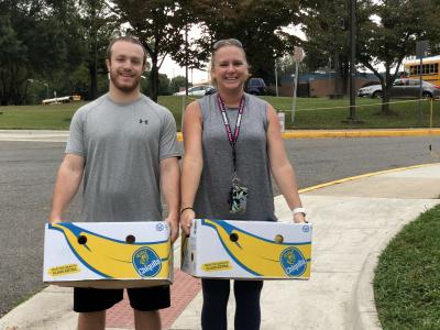 photo of two teachers holding boxes of bananas