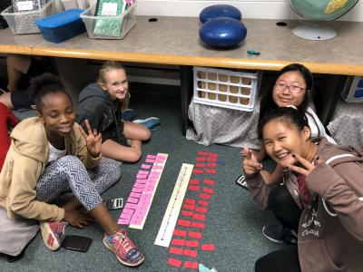 photo of students seated on the floor with cards and numberlines