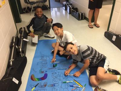 Photo of students coloring on large paper on floor